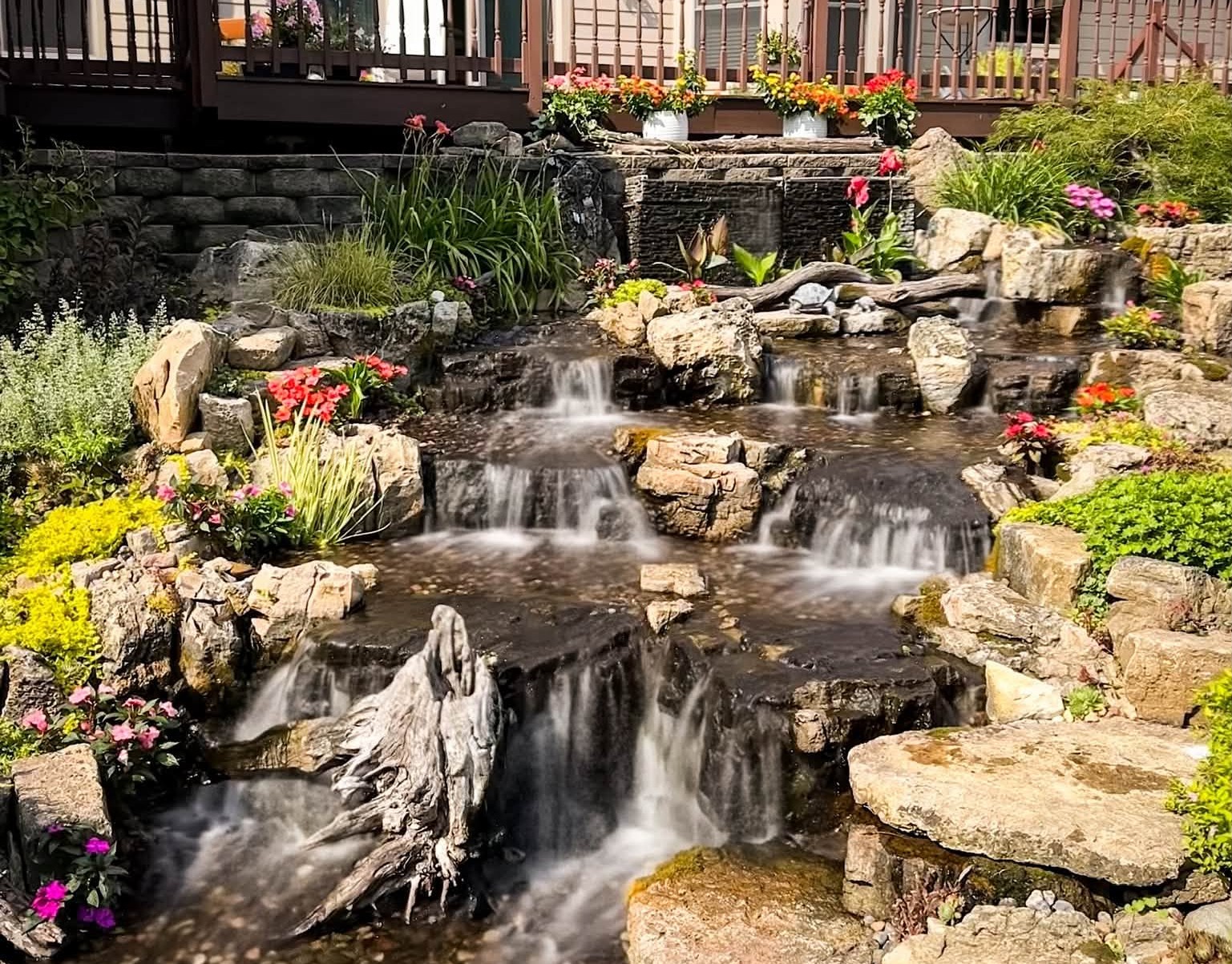 Pondless Waterfall in Backyard with many plants to soften